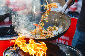 chef cooks Chinese noodle wok at street food festival