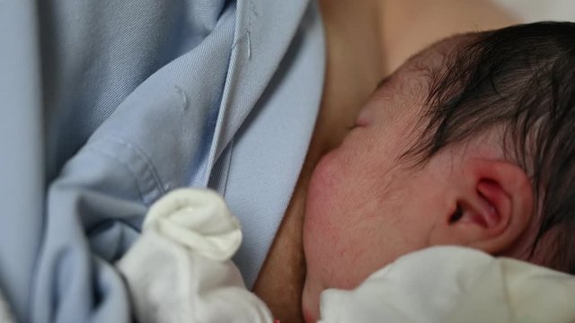 4K Asian woman breastfeeding newborn baby. Mother breastfeeding newborn girl lying in bed. Concept breast feeding. Baby eating mother's milk. Mom breastfeeding infant
