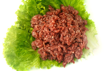 raw minced meat isolated on white background with green leaves and condiments.