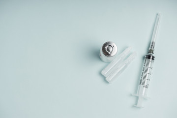 Medicine bottle with vaccine and disposable syringe closeup on blue background. Health pharmacy pharmacology concept with space for text