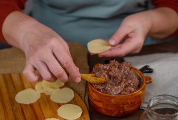 Woman cook sculpts dumplings with his hands, close-up. On the table is minced meat and rolled circles of dough