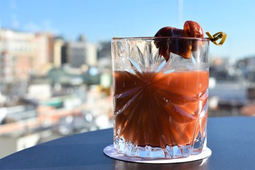 Tomato juice cocktail in glass with a dried tomato dressing and a blurred city background