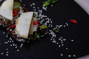 Mini sandwich with radish, black bread, chili pepper, sesame seed.