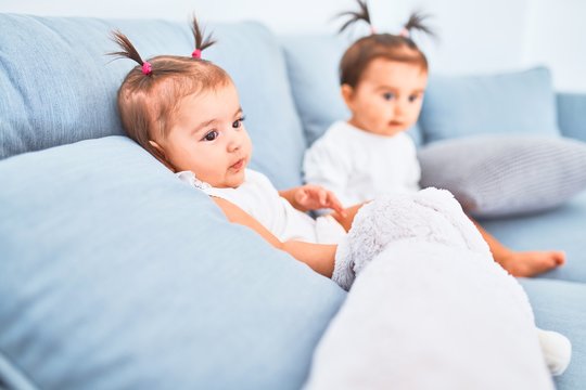 Beautiful infant happy girls playing together at home kindergarten sitting on the sofa