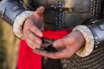 hands of a medieval warrior, close-up, stained with earth. Holds the earth in his hands. hands in the ground