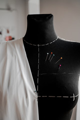 Mannequin with fabric on the shoulder and stuck pins into the fabric in design studio for sewing and tailoring, special education