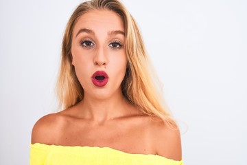 Naklejka premium Young beautiful woman wearing yellow t-shirt standing over isolated white background scared in shock with a surprise face, afraid and excited with fear expression