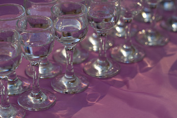 Glasses with vodka served on lilac table, close up 