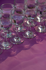 Glasses with vodka served on lilac table, close up, vertical orientation
