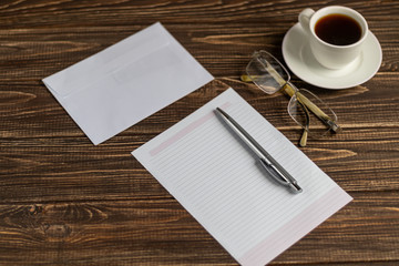 A wooden office desk with many things on it. Diary with pen, Samsung phone. White cup of coffee. Top view with copy space,