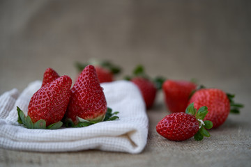 Detail of ripe red strawberry. Red fresh strawberries on a pale cloth, blurry background.