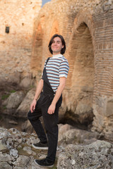 Young man posing in the field and with a bridge in the background. Enjoying the outdoors