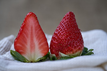 Slice of ripe red strawberry. Red fresh strawberries on a pale cloth, blurry background.