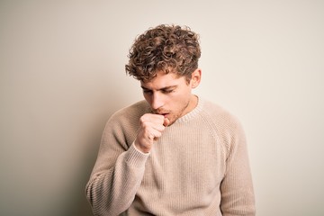 Fototapeta na wymiar Young blond handsome man with curly hair wearing casual sweater over white background feeling unwell and coughing as symptom for cold or bronchitis. Health care concept.