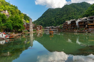 Fototapeta na wymiar Panoramic view of the old town with the Wanmingta Pagoda and the bridge in the background. Green water reflects the landscape in Fenghuang Ancient Town, Hunan province, China