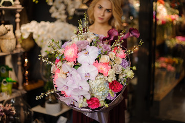 Woman holding a spring bouquet of pink orachids, hydrangeas and roses decorated with branches