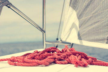 Sailboat deck with stacked red rope while sailing.