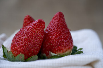 Detail of ripe red strawberry. Red fresh strawberries on a pale cloth, blurry background.