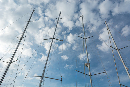 Conceptual view of frout sail boat masts under cloudy sky.