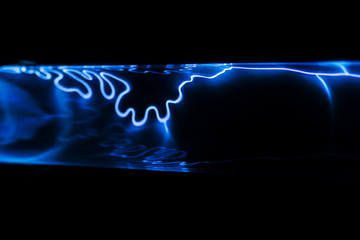 Blue electric discharge on a black background. Bright lightning in a plasma lamp. Mystical glow.