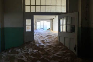 Abandoned and forgotten building and room left by people and being taken over by encroaching sandstorm, Kolmanskop ghost town, Namib Desert