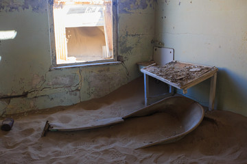 Abandoned and forgotten building and room left by people and being taken over by encroaching sandstorm, Kolmanskop ghost town, Namib Desert