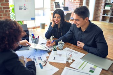 Young beautiful couple applying for mortgage. Sitting smiling happy meeting with real state agent signing mortgage loan at bank
