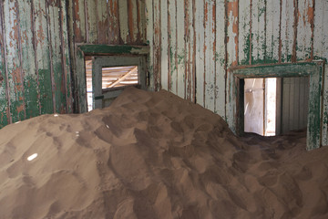 Abandoned and forgotten building and room left by people and being taken over by encroaching sandstorm, Kolmanskop ghost town, Namib Desert