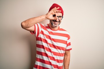 Naklejka premium Middle age hoary man wearing striped t-shirt glasses and cap over isolated white background doing ok gesture with hand smiling, eye looking through fingers with happy face.
