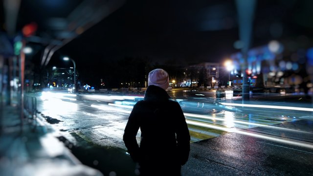 REAR VIEW OF WOMAN STANDING IN CITY AT NIGHT