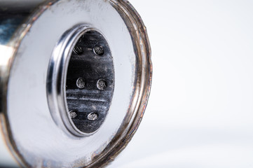 Close-up of the inlet of a new muffler for a car made of stainless steel on a gray background