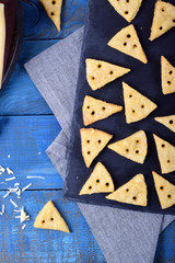 Crackers shaped as cheese slices with holes on the blue wooden background