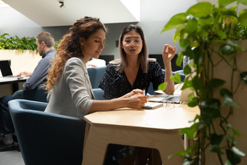Multiethnic female employees busy cooperating in office
