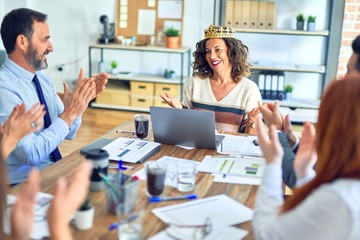 Group of business workers smiling happy and confident. Working together with smile on face applauding one of them wearing king crown at the office