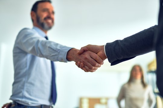 Business workers standing together shaking hands at the office