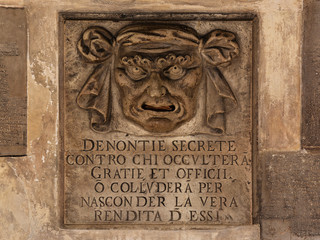 old stone relief of a mans face with open mouth