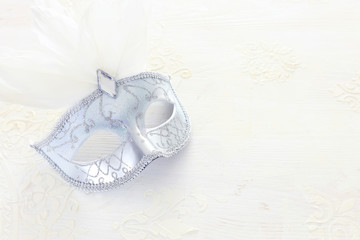Photo of elegant and delicate Venetian mask over white wooden background