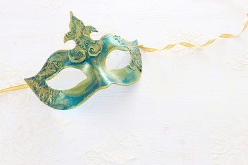 Photo of elegant and delicate gold Venetian mask over white wooden background
