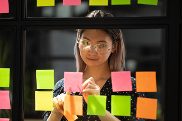 Millennial Asian employee write ideas on sticky notes