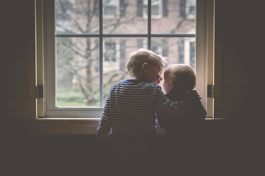 TWO BROTHERS LOOKING THROUGH WINDOW