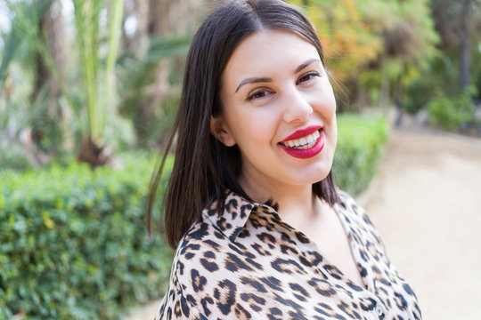 Young beautiful woman with red lips smiling happy at garden