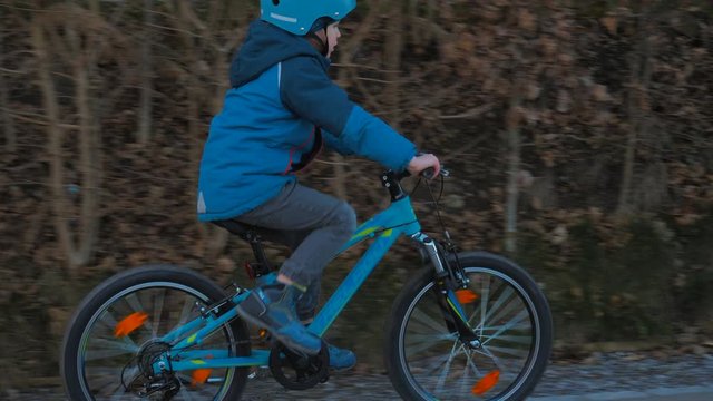Kleiner s&uuml;sser Junge f&auml;hrt mit seinem Velo auf der Strasse und tr&auml;gt einen Helm