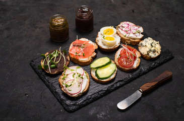 Healthy vegetarian sandwiches. Assorted whole grain vegetable bruschettas with microgreen. Eating right concept, food background. Sandwiches on slate board.