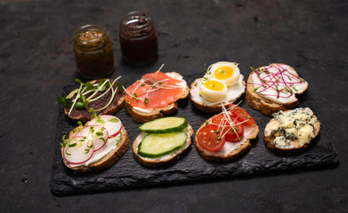 Healthy vegetarian sandwiches. Assorted whole grain vegetable bruschettas with microgreen. Eating right concept, food background. Sandwiches with creamy cheese, cucumber, eggs, salmon,
