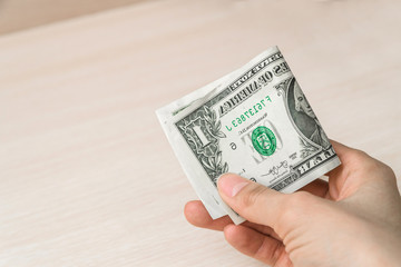 Hand with a one-dollar bill on a wooden background, an image of money