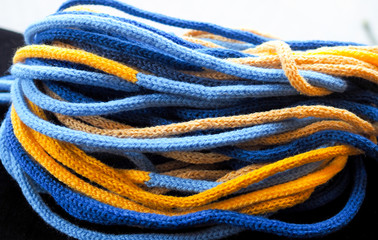 scarf made of knitted ropes yellow light and dark blue. Close up. Natural background