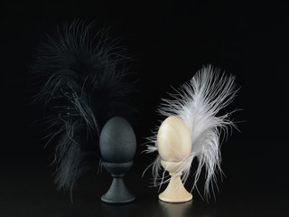 Two eggs white and black on stands with feathers. The concept of Valentine's day