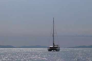A  cruise sailing catamaran lagoon 450 with a Bermuda sloop-type rig goes past the islands of the Croatian Riviera on a sunny summer day. Adriatic Sea of the Mediterranean region. District of Dalmatia