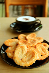 Vertical Image of a Plate of  French Palmier Pastries with Blurry Cappuccino in the Backdrop