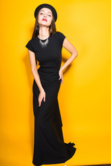 Naklejka premium mannered arched body and with an arrogant look, a pretty woman in a black evening dress stands akimbo